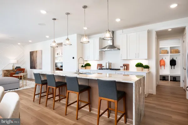 a kitchen that has a lot of cabinets in it with stainless steel appliances granite countertop a stove a sink a dining table and chairs with wooden floor