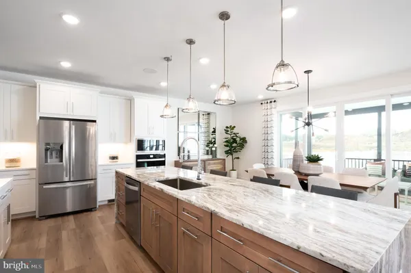 a kitchen with stainless steel appliances kitchen island granite countertop a refrigerator a sink dishwasher a oven and a dining table with the view
