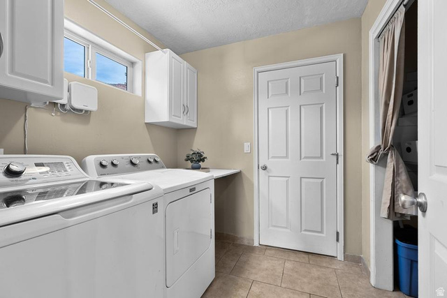 225 Falcon Court Ivins, UT 84738 - Photo 18 of 47 Laundry room featuring washing machine and dryer, a textured ceiling, light tile patterned floors, and cabinet space