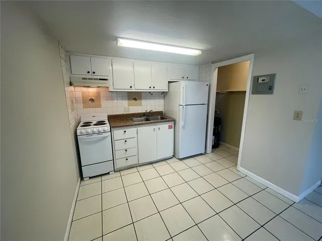 a kitchen with white cabinets a refrigerator and a stove top oven