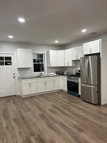 a kitchen with granite countertop a refrigerator and a stove top oven