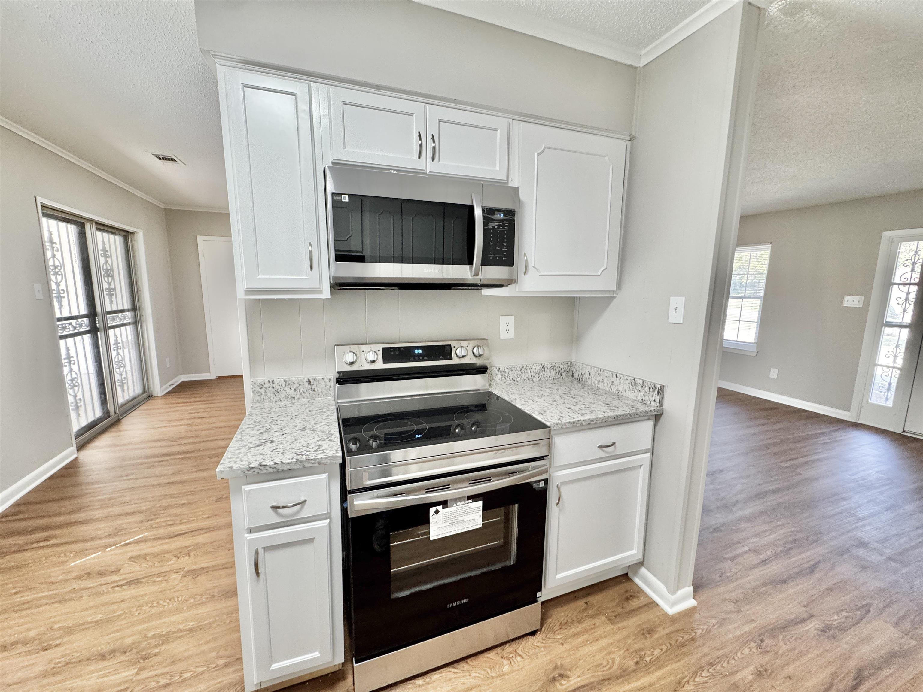 5095 Bowie Road Memphis, TN 38109 - Photo 7 of 25 Kitchen with appliances with stainless steel finishes, a textured ceiling, white cabinetry, plenty of natural light, and ornamental molding