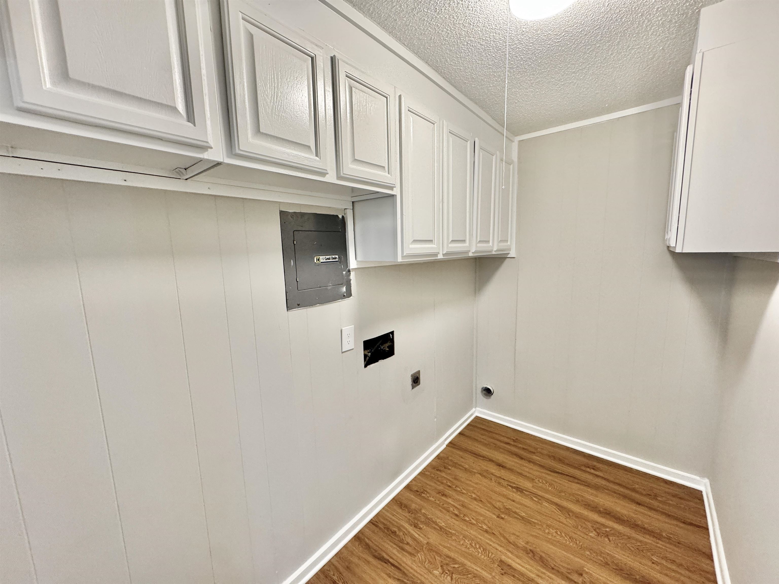 5095 Bowie Road Memphis, TN 38109 - Photo 8 of 25 Laundry area featuring cabinet space, wood finished floors, wood walls, hookup for an electric dryer, and a textured ceiling