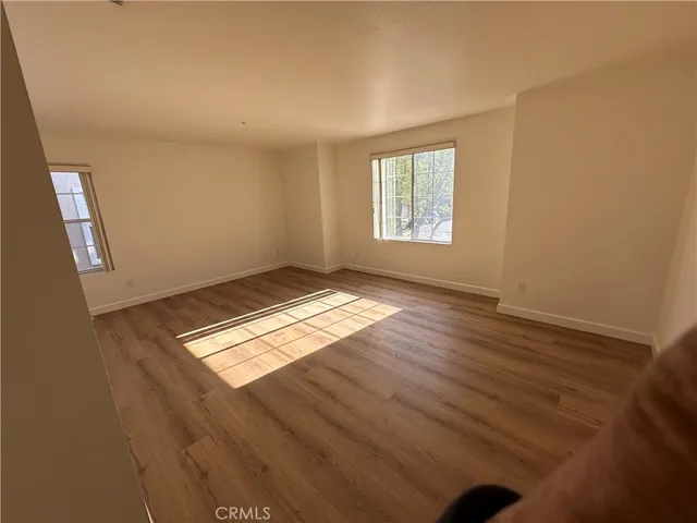 an empty room with wooden floor and windows