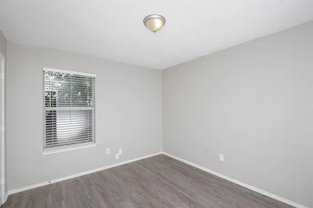 a view of an empty room with a window and wooden floor