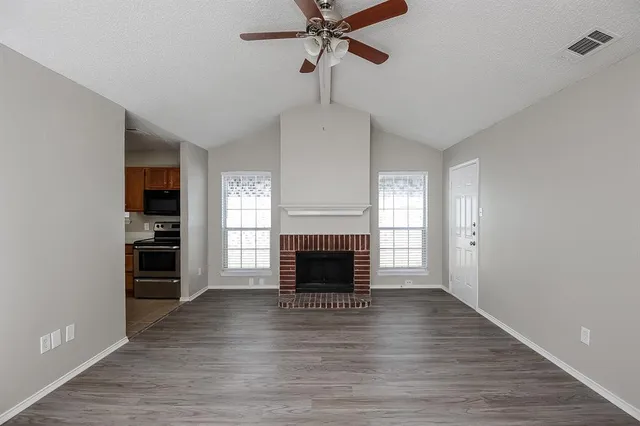 wooden floor fireplace and windows in an empty room