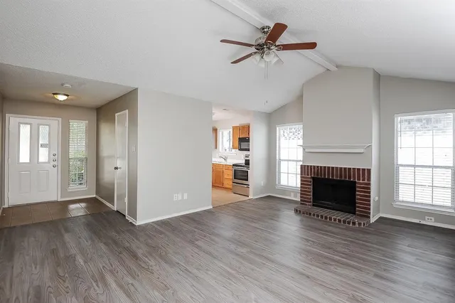 an empty room with wooden floor fireplace and windows