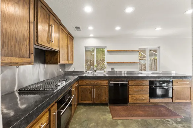a kitchen with stainless steel appliances granite countertop a stove a sink and a microwave