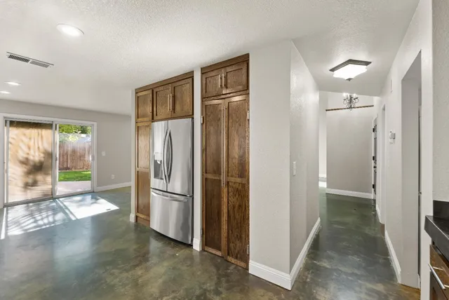 a view of a refrigerator in kitchen and an empty room