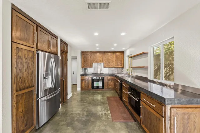 a kitchen with stainless steel appliances granite countertop a refrigerator a stove a sink and a refrigerator