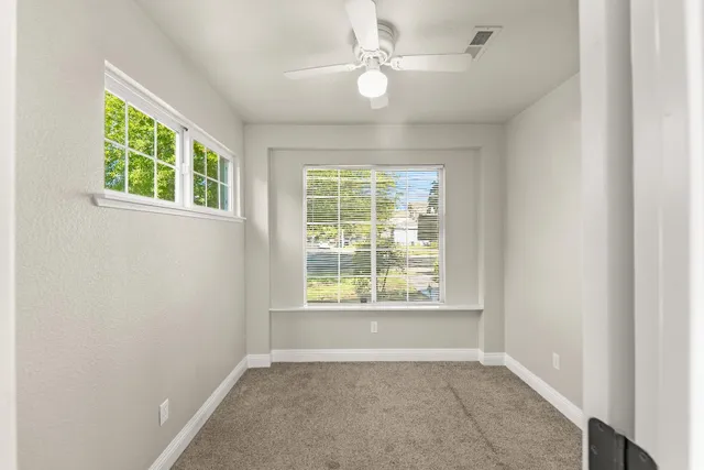 an empty room with a window and a fan