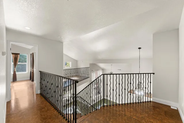 a view of a hallway with wooden floor and windows