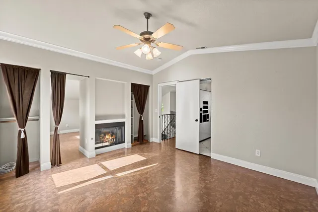 a view of a livingroom with a fireplace a ceiling fan and wooden floor