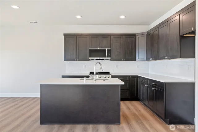 a kitchen with kitchen island granite countertop a sink stove and microwave