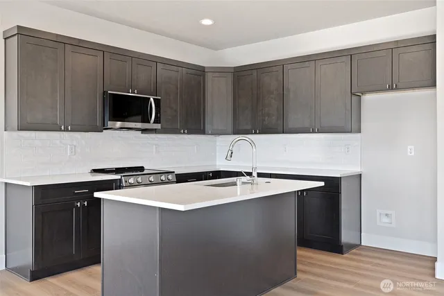 a kitchen with kitchen island granite countertop a sink stove and microwave