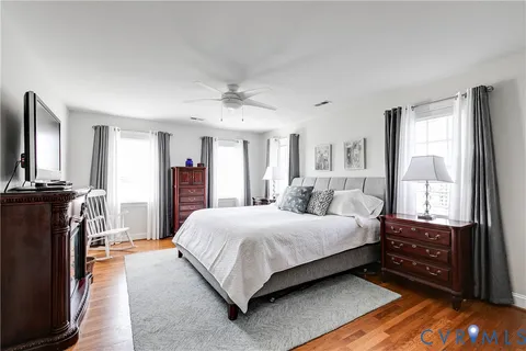 a bedroom with a bed flat screen tv and windows