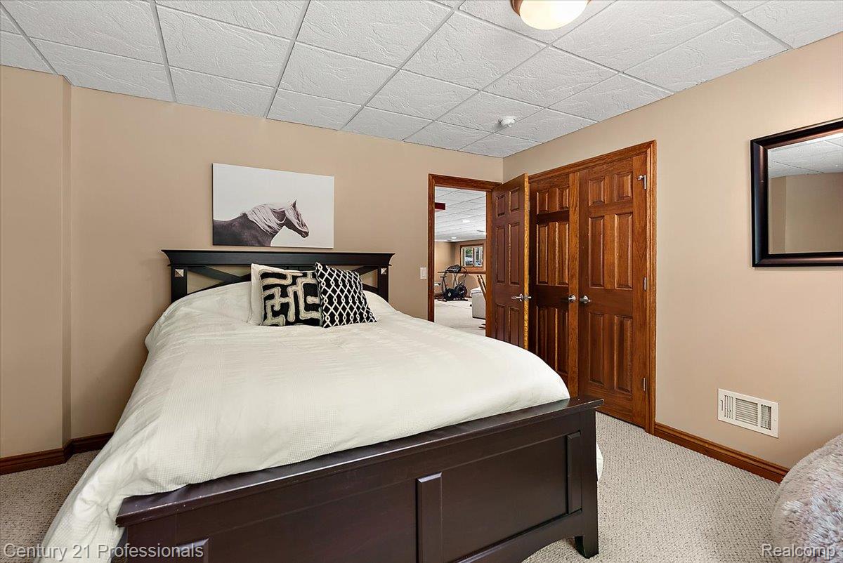 9867 Rainbow Ridge Drive Schoolcraft, MI 49087 - Photo 56 of 82 Carpeted bedroom featuring a dark wood bed frame, light beige wall paint, a drop ceiling, and wood-paneled double closet doors