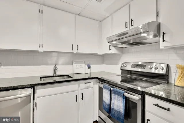 a kitchen with stainless steel appliances granite countertop white cabinets and a stove