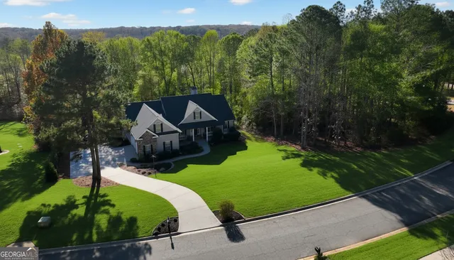 a view of a house with a big yard plants and large trees