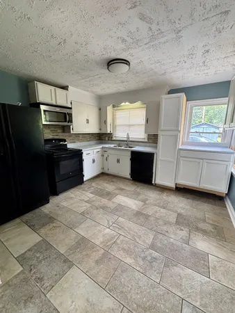 a large kitchen with kitchen island granite countertop a stove a sink dishwasher and a refrigerator