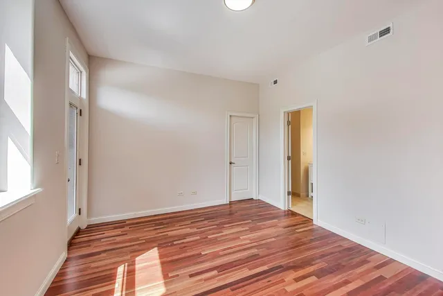 a view of empty room with wooden floor and fan