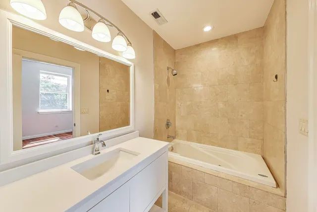 a bathroom with a bathtub shower sink and mirror