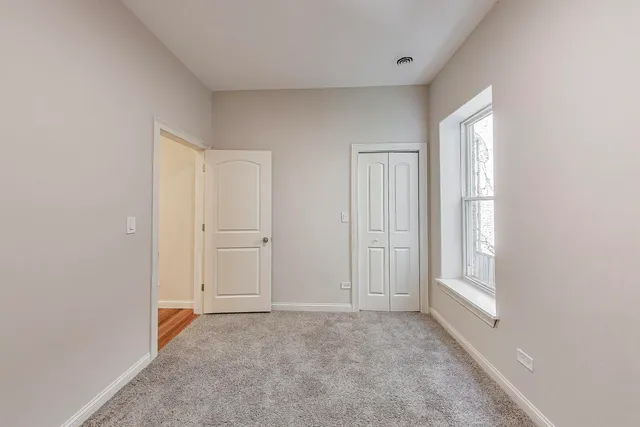 a view of empty room with windows and wardrobe