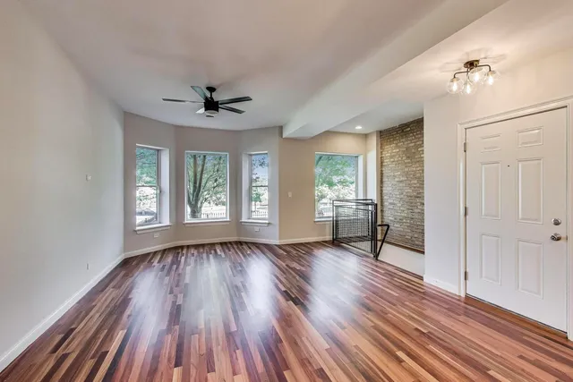 a view of an empty room with a window and wooden floor
