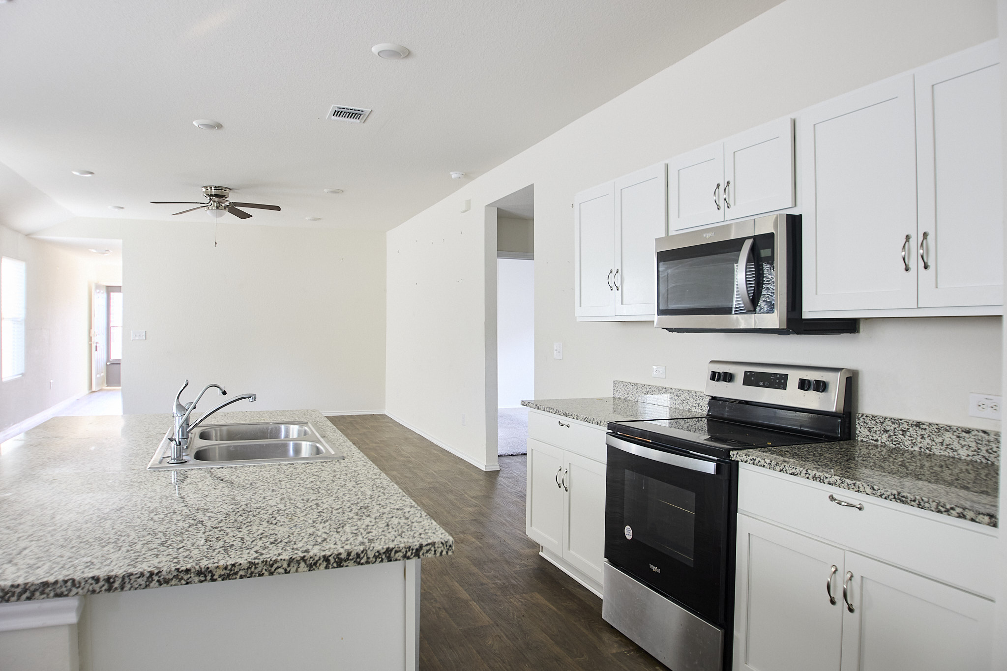 12008 Roving Pass Elgin, TX 78621 - Photo 7 of 20 Kitchen featuring stainless steel w/ black appliances, a center island with sink, white cabinetry, and granite countertops
