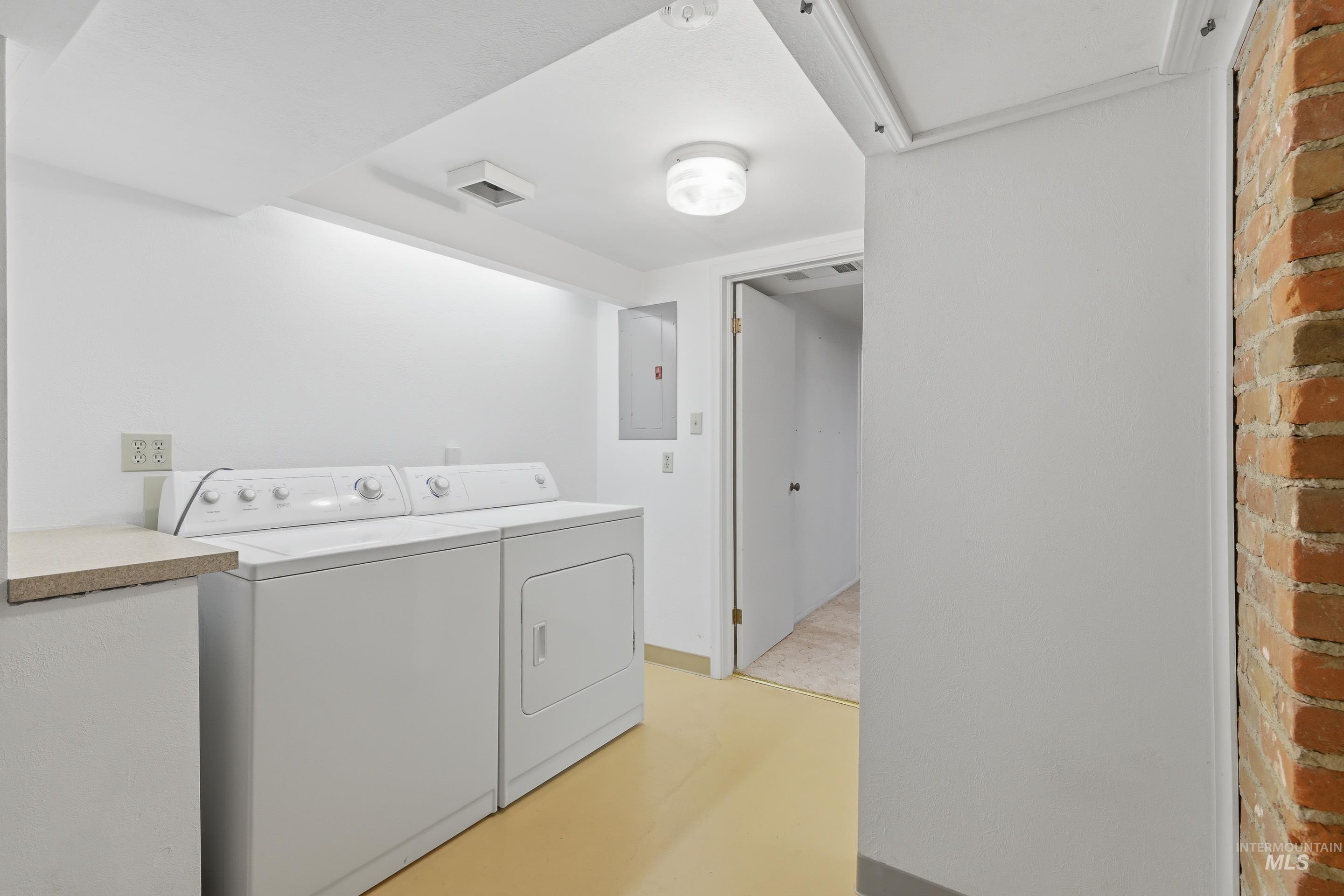 504 West Howe Street Boise, ID 83706 - Photo 28 of 47 Dedicated laundry area featuring a washer and dryer, light-toned flooring, exposed brick wall, and overhead lighting