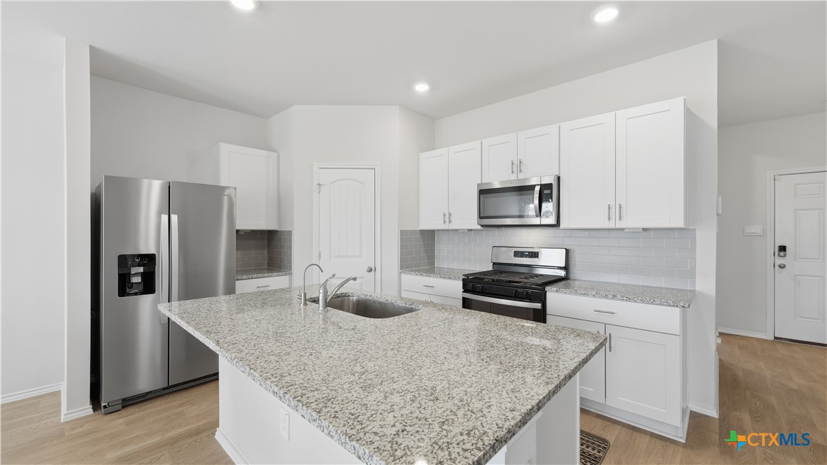 1708 Violeteared Way Lockhart, TX 78644 - Photo 5 of 25 a kitchen with stainless steel appliances granite countertop a sink stove and refrigerator