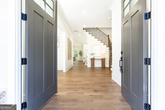 a view of a hallway with wooden floor windows and a kitchen view