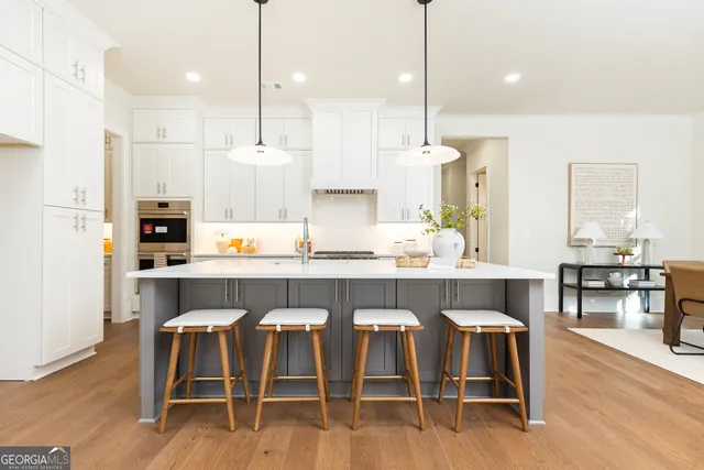a kitchen with kitchen island granite countertop a table chairs sink and cabinets