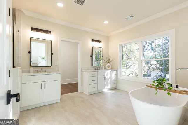 a spacious bathroom with a tub double sink and mirror
