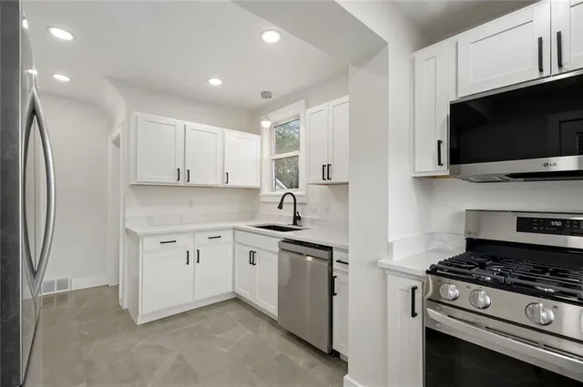 a kitchen with stainless steel appliances a sink a stove a microwave and cabinets