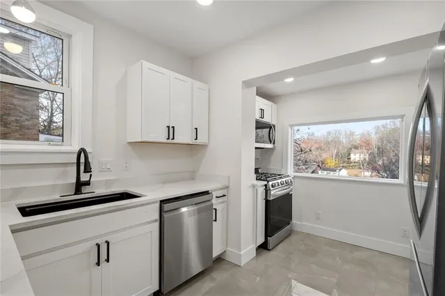 a kitchen with granite countertop white cabinets and stainless steel appliances