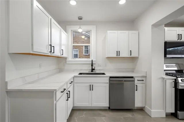 a kitchen with white cabinets appliances and a sink