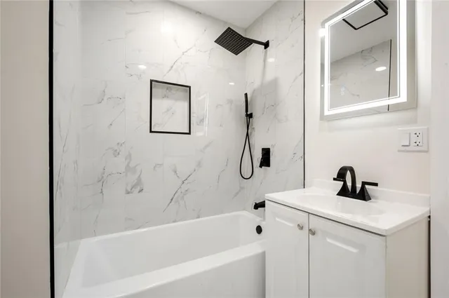 a white bath tub sitting next to a white sink and vanity