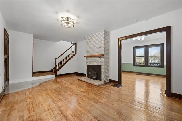 a view of an empty room with wooden floor a fireplace
