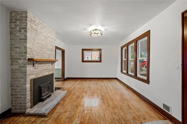 a view of a livingroom with wooden floor a fireplace and window