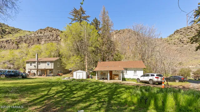 a front view of a building with a garden and trees