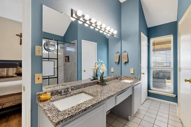 a en suite bathroom with a granite countertop shower a sink and a mirror