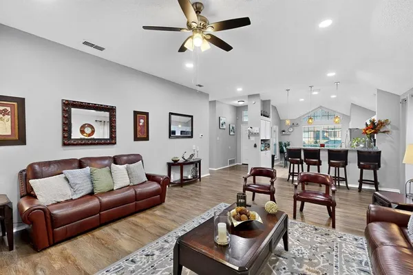 a living room with furniture a wooden floor and a ceiling fan