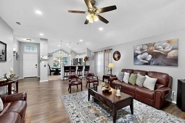 a living room with furniture kitchen view and a chandelier