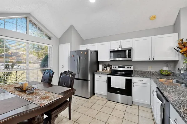 a kitchen with stainless steel appliances granite countertop a stove top oven a sink dishwasher a dining table and chairs with wooden floor