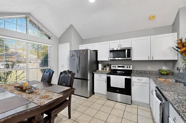 a kitchen with stainless steel appliances granite countertop a stove top oven a sink dishwasher a dining table and chairs with wooden floor