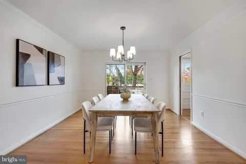 a dining room with wooden floor a chandelier a wooden table and chairs
