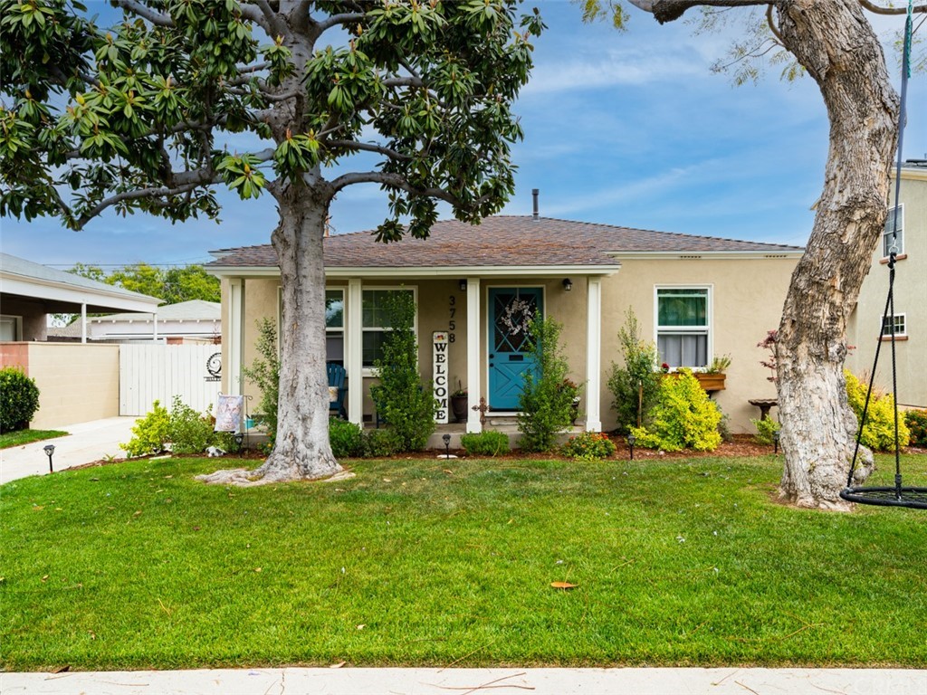 a front view of a house with a yard and tree