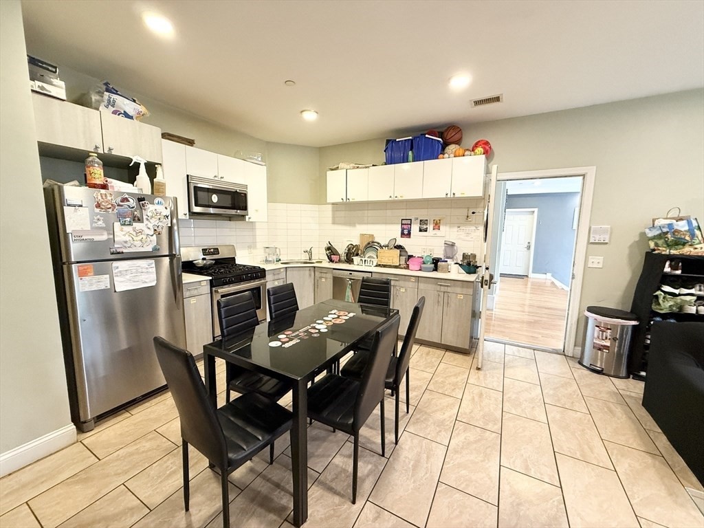299 Dudley Street, Unit 2 Boston, MA 02119 - Photo 4 of 6 a kitchen with stainless steel appliances kitchen island granite countertop a table chairs refrigerator and a stove top oven