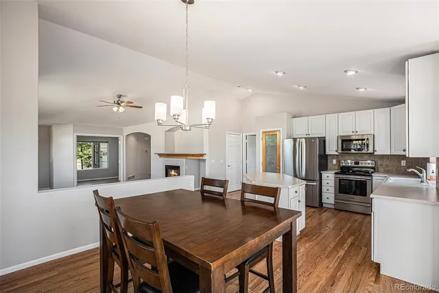 a kitchen with stainless steel appliances granite countertop a kitchen island a stove a table a sink and a refrigerator